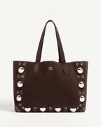A Valentino Garavani Nellcôte suede shopping bag, crafted in soft suede with ball studs, rivets, and palladium-finish hardware. Features a removable inner pouch and double handles for versatile carrying options.